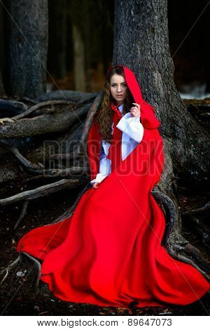 beautiful woman with red cloak posing in the woods