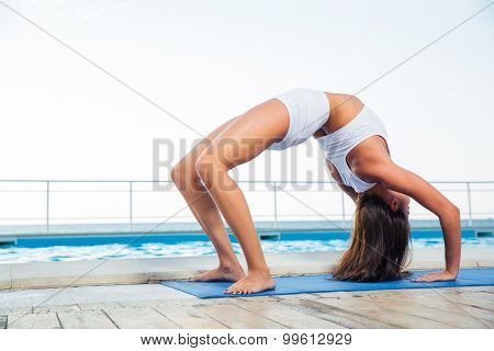 Young girl standing in bridge pose outdoors 