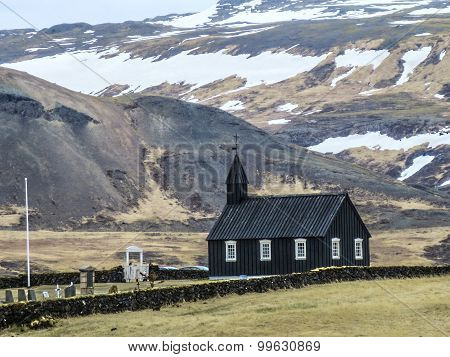 Black Wooden Church In Front Of A Mountain Chain In Budir, Iceland