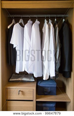 Clothes hang on a shelf in a designer clothes store, modern closet with row of cloths hanging