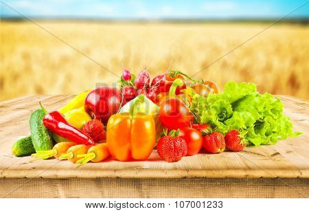 fruits and vegeetables on wooden desk and autumn field on background