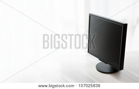 Computer LCD flat panel monitor by the window fading into white. Focus is on forehand edge of LCD monitor.