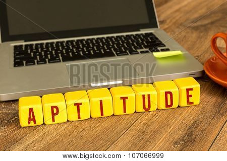Aptitude written on a wooden cube in front of a laptop