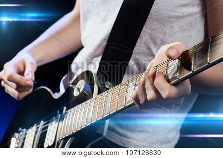 music, people, musical instruments and entertainment concept - close up female musician hands playing electric guitar with mediator