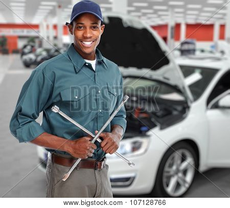 Smiling car mechanic with wrench in auto repair service. 