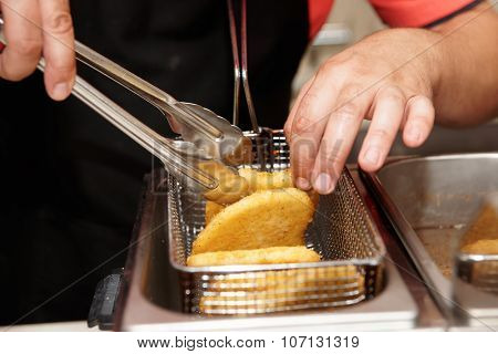 Chef is cooking chicken nuggets in a deep fryer