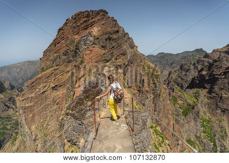 MADEIRA, PORTUGAL - JUNE 30, 2015: Young girl on the winding mountain trekking path at Pico do Areeiro, Madeira, Portugal.