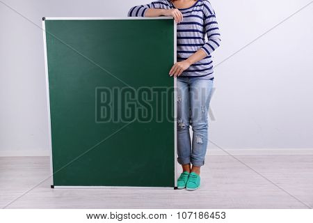 Woman in causal with green blackboard on grey background, close up