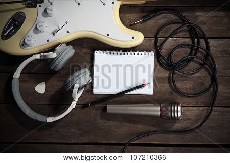 Electric guitar with headphones and microphone on wooden background