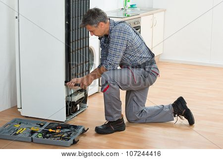 Handyman Repairing Refrigerator At Home