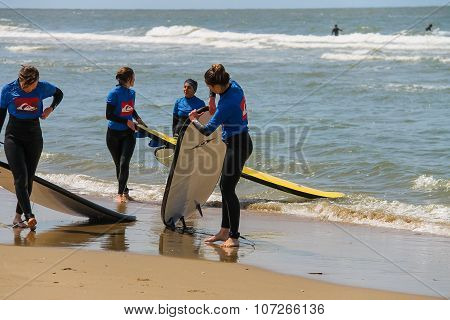 Young Surfer Friends In Wetsuits Walking Along The Shore With Their Surfing Boards. Zandvoort, The N