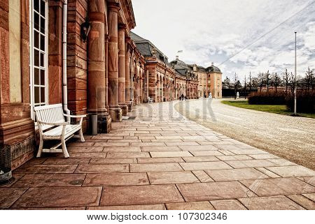 Red sandstone palace walkway with row of smooth columns.