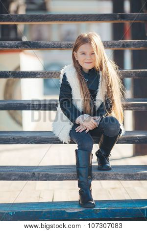Little girl sitting on the steps near the house
