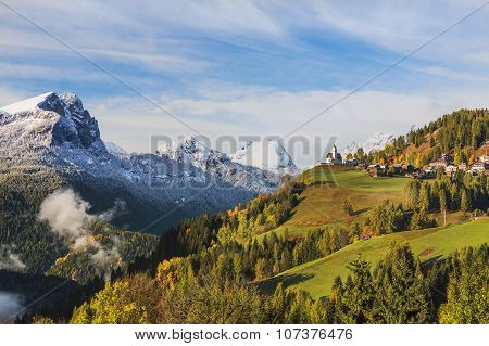 Picturesque Autumn Landscape With A Church On The Hill And The Snow-capped Mountains.