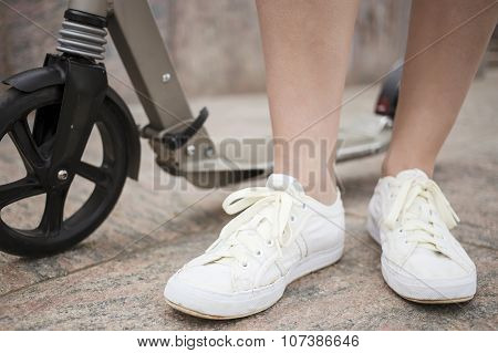 Scooter And Feet Of A Man Who Stands On The Granite Pavement