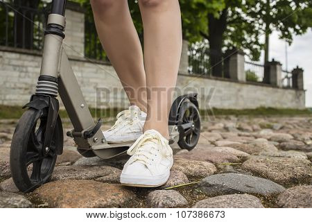 Scooter And Feet Of A Man Who Stands On The Stone Pavement In Europe