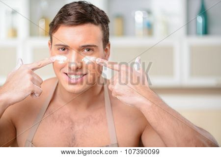 Young smiling man puts some flour on his face.