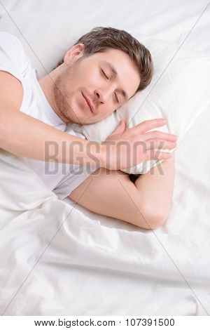 Young man sleeps in his bed.
