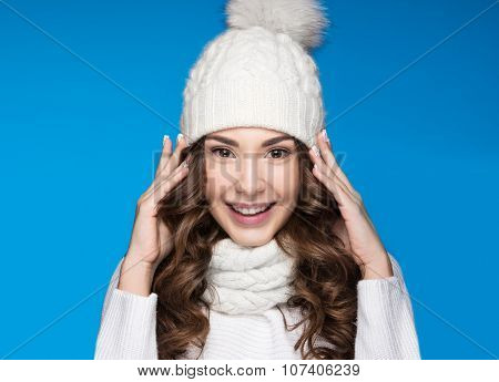 Beautiful girl with gentle makeup, design manicure and smile in white knit hat. Warm winter image. B