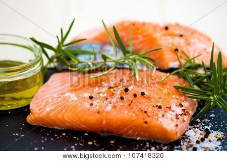 Portions Of Fresh Raw Salmon Fillets With Aromatic Herbs And Olive Oil