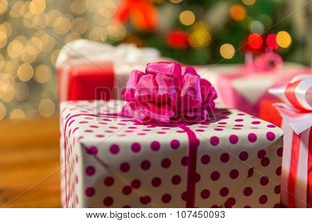 christmas, holidays, presents, new year and celebration concept - close up of gift boxes over christmas tree lights
