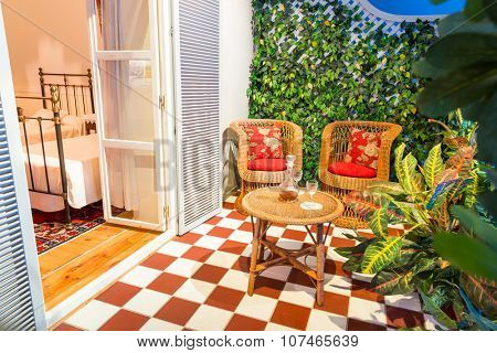 Cosy balcony with cane furniture and glasses of vine in the hotel room