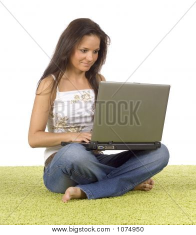 Giovane donna con il computer portatile sul tappeto verde