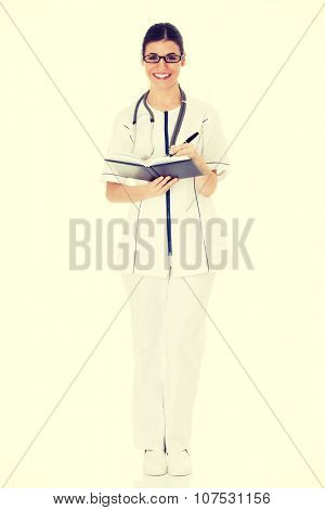 Young female doctor wirting in a book