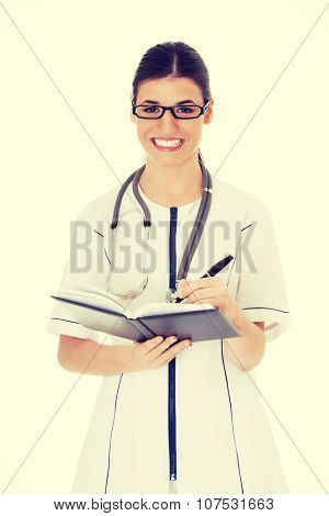 Young female doctor wirting in a book