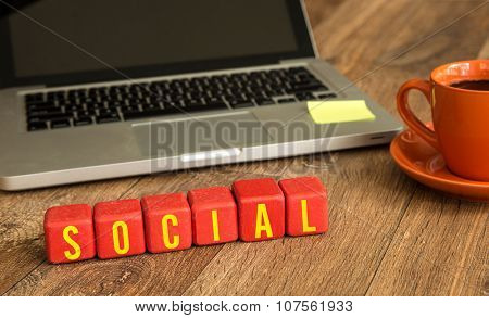 Social written on a wooden cube in front of a laptop