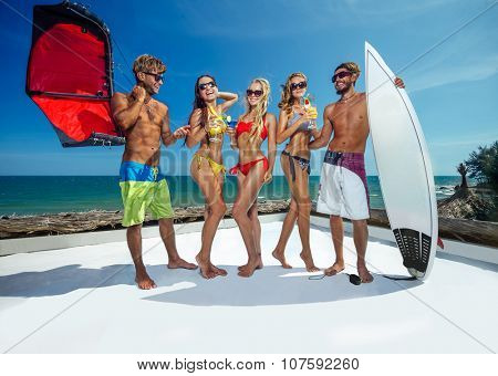 Surfer and kiter boys with beautiful girls group stay on beach 