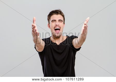 Handsome young attractive man singing emotionaly with closed eyes