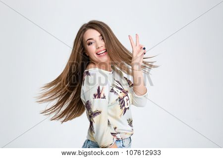 Portrait of a happy casual woman showing two fingers sign isolated on a white background