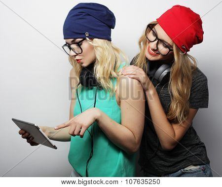 two hipster girls friends use digital tablet, studio shot over gray vackground