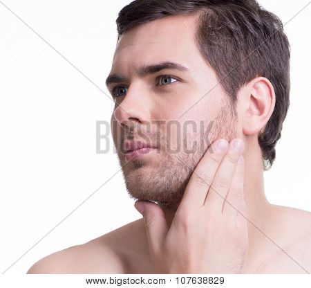 Close-up portrait of handsome young man with hand near the face looking sideways on white background.