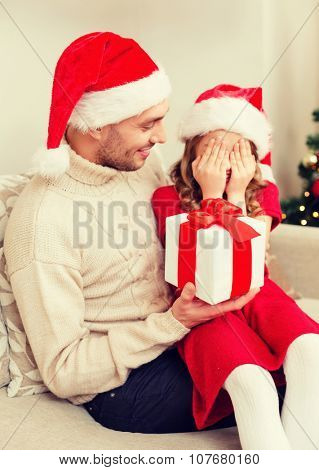 family, christmas, x-mas, winter, happiness and people concept - smiling daughter with closed eyes waiting for a present from fathe