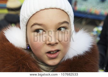 Portrait of brown-eyed girl (9-10 years) in a knitted hat and fur jacket