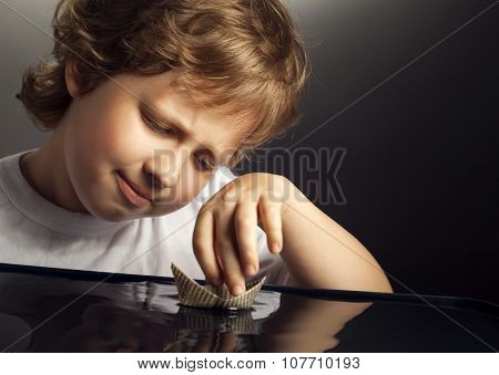 boy play in paper ship in water puddel