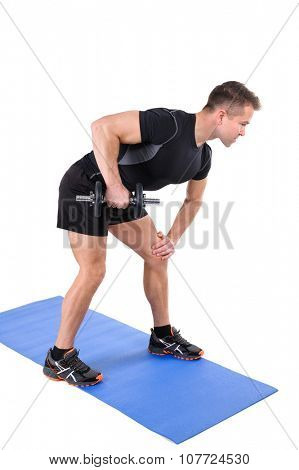 Young man shows starting position of Standing Tricep Dumbbell Kickback workout, isolated on white