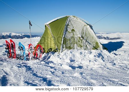 Tent winter mountains.Tent stands in the mountains in the snow. Snowshoes are beside the tent.