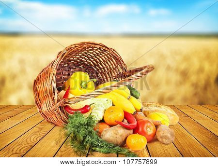 fruits and vegeetables and other food on wooden desk and autumn field on background
