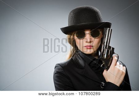 Female spy with weapon against gray