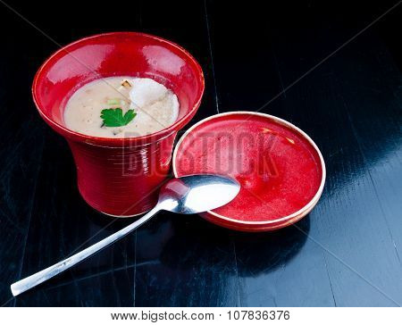Vegetable soup served in a red cup on a black wooden table