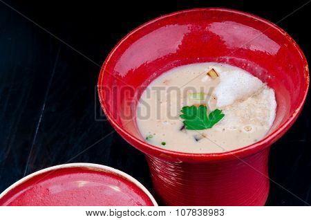 Vegetable soup served in a red cup on a black wooden table