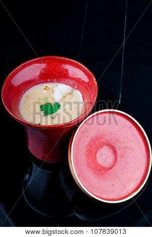 Vegetable soup served in a red cup on a black wooden table
