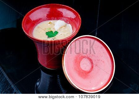 Vegetable soup served in a red cup on a black wooden table