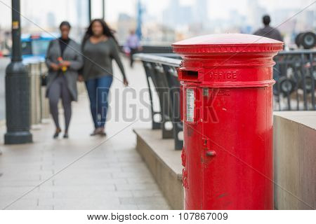 Her majesty Royal mail.  Red post box and two women walking on the street