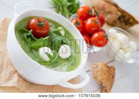 Arugula and tomatoes puree soup in white bowl