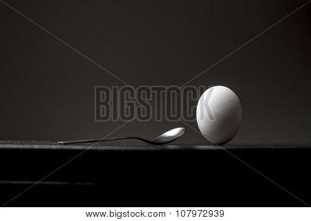 Inverted Upside Down Egg Stands On A Black Wooden Table