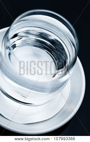 Single glass of clean clear drinking water tilted tilt view close up macro on the table